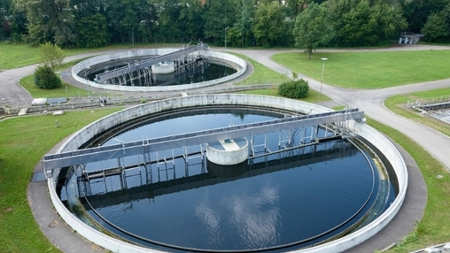 Two large circular clarifiers at a water treatment plant viewed from above, surrounded by green grass
